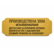 Златиста гравирана индустриална табелка с надпис „ПРОИЗВОДСТВЕНА ЗОНА“ и инструкции за безопасност при работа